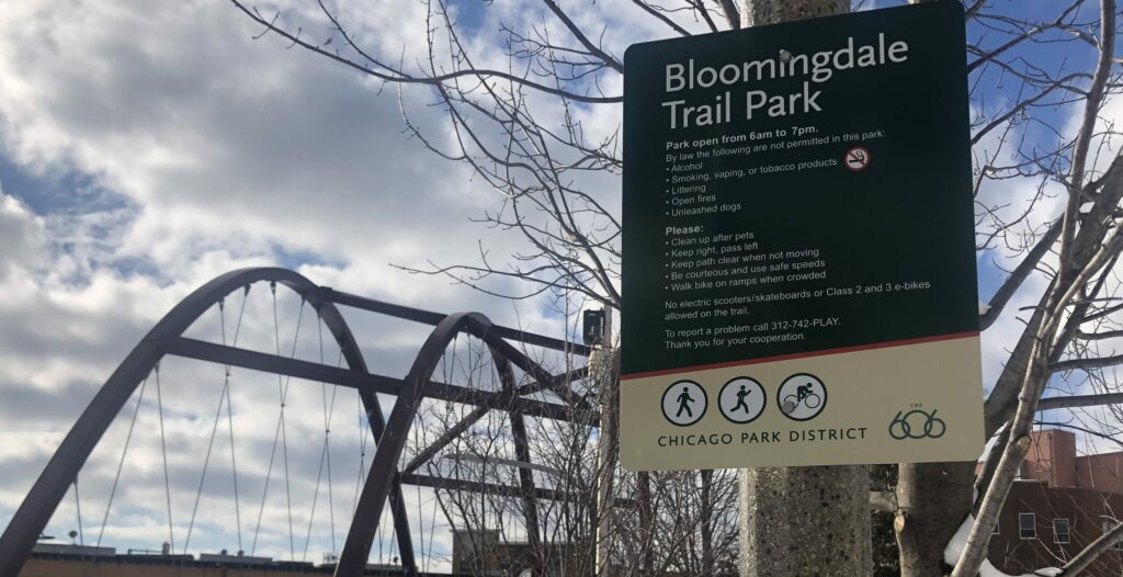 Bloomingdale Trail sign with iconic arched bridge in background.